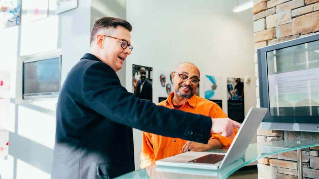 Man showing something on a laptop to another man