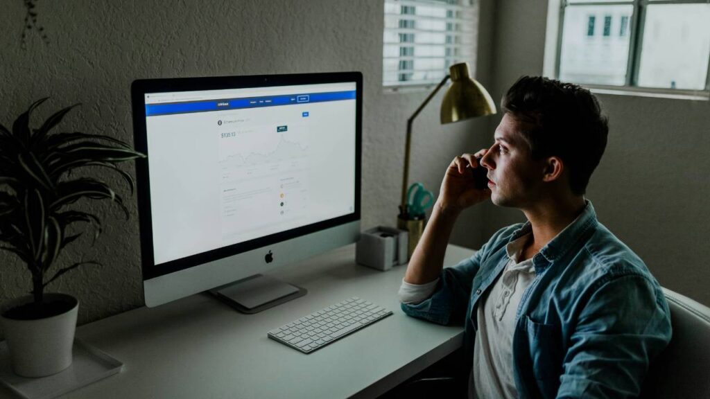 A man having a call while looking at his computer monitor