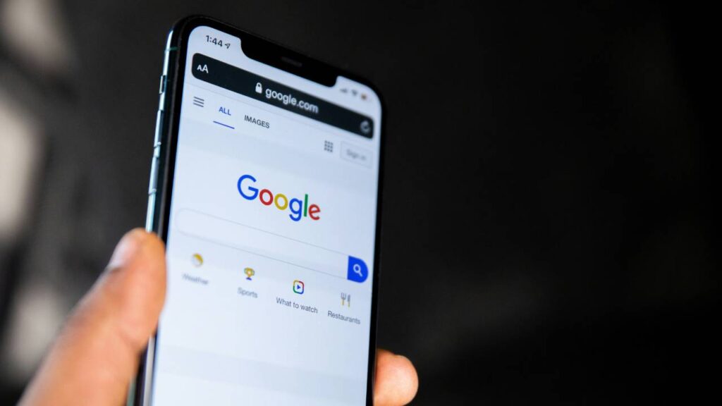 A photo of a hand holding a phone with Google's web browser on its screen