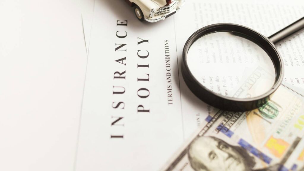 A photo of a magnifying glass and a dollar bill placed on an insurance document