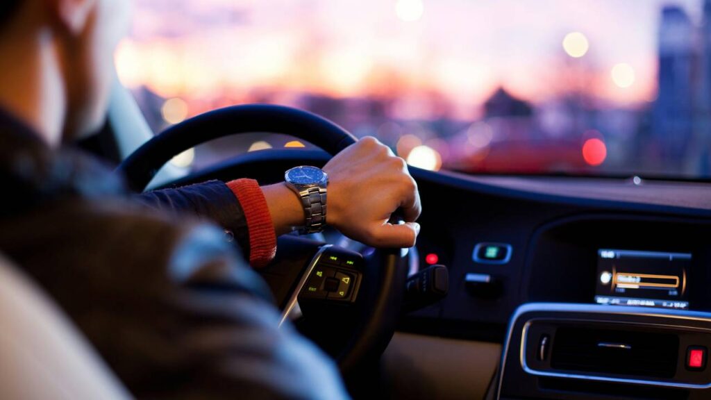 A man with an expensive watch on his wrist driving an automobile