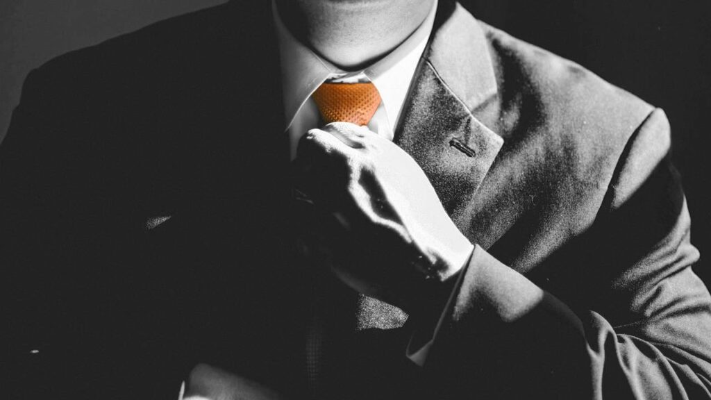 A black and white photo of a businessman touching his tie