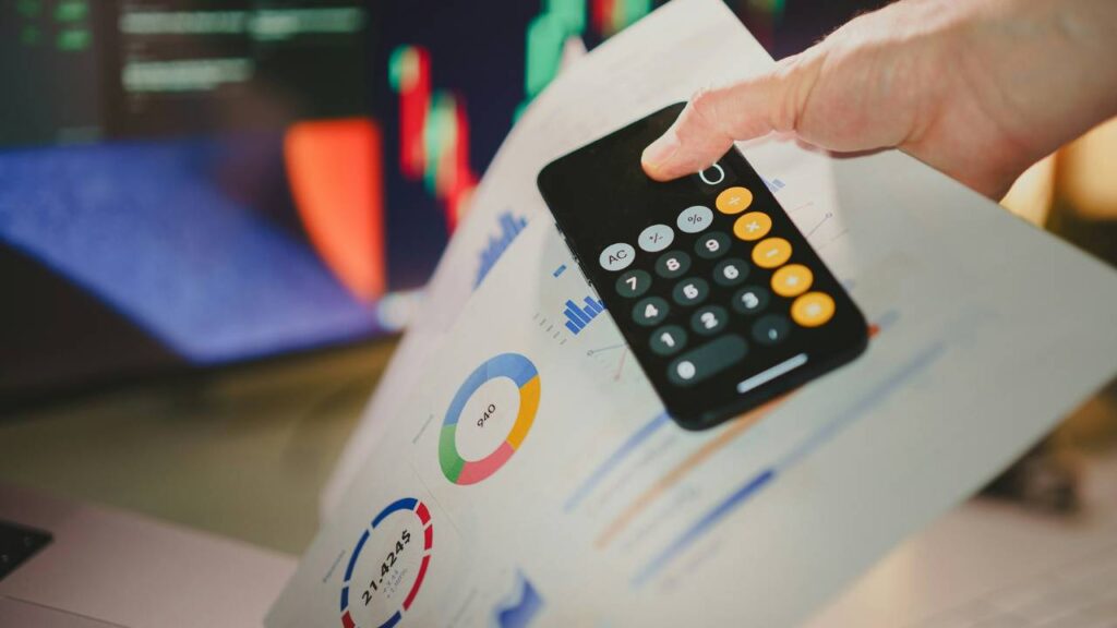 A close-up photo of a person holding a phone with the calculator app on it 