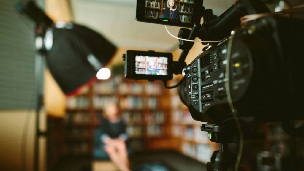 Camera crew filming a woman in a library 